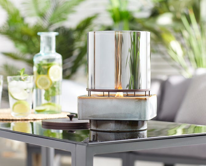 An Outdoor Fragrance Flame warmer on a patio table